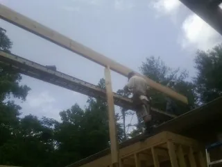 Carpenter setting a ridge beam over a new addition frame — Ice Dam Removal by Roofing Brothers in Stoneham