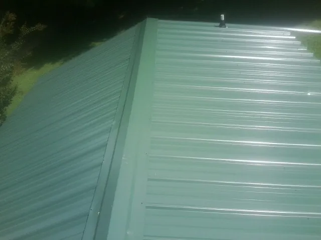 New green metal panels meeting at the ridge of a roof — Flat Roof Repair work by our crew in Stoneham