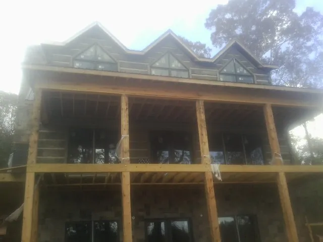 Dormers and porch framing on a large log home under construction — Roof Coating work by our crew in Stoneham