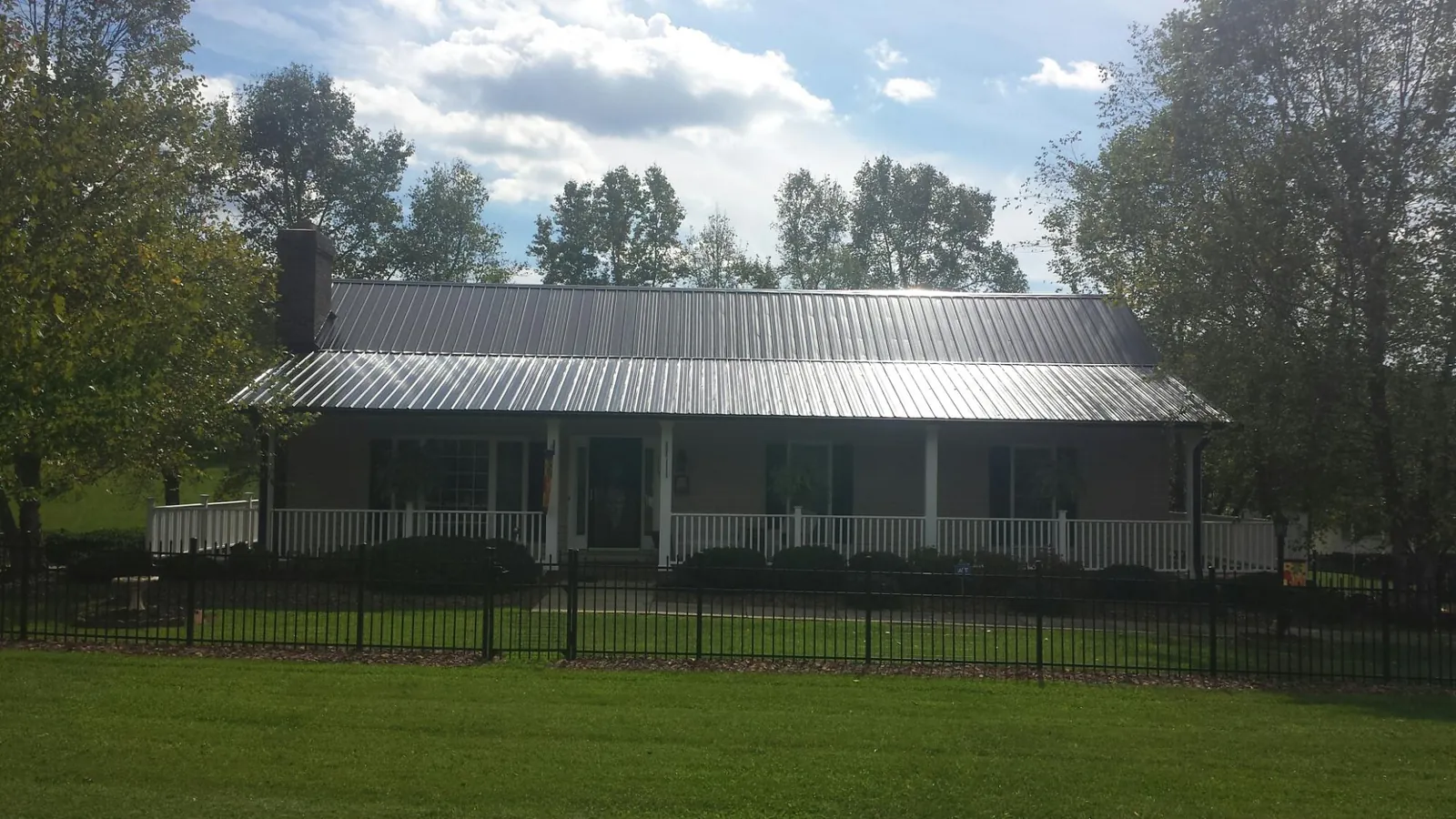 Gray metal roof on a brick ranch with a full width front porch — Gutter Guard Installation work by our crew in Stoneham