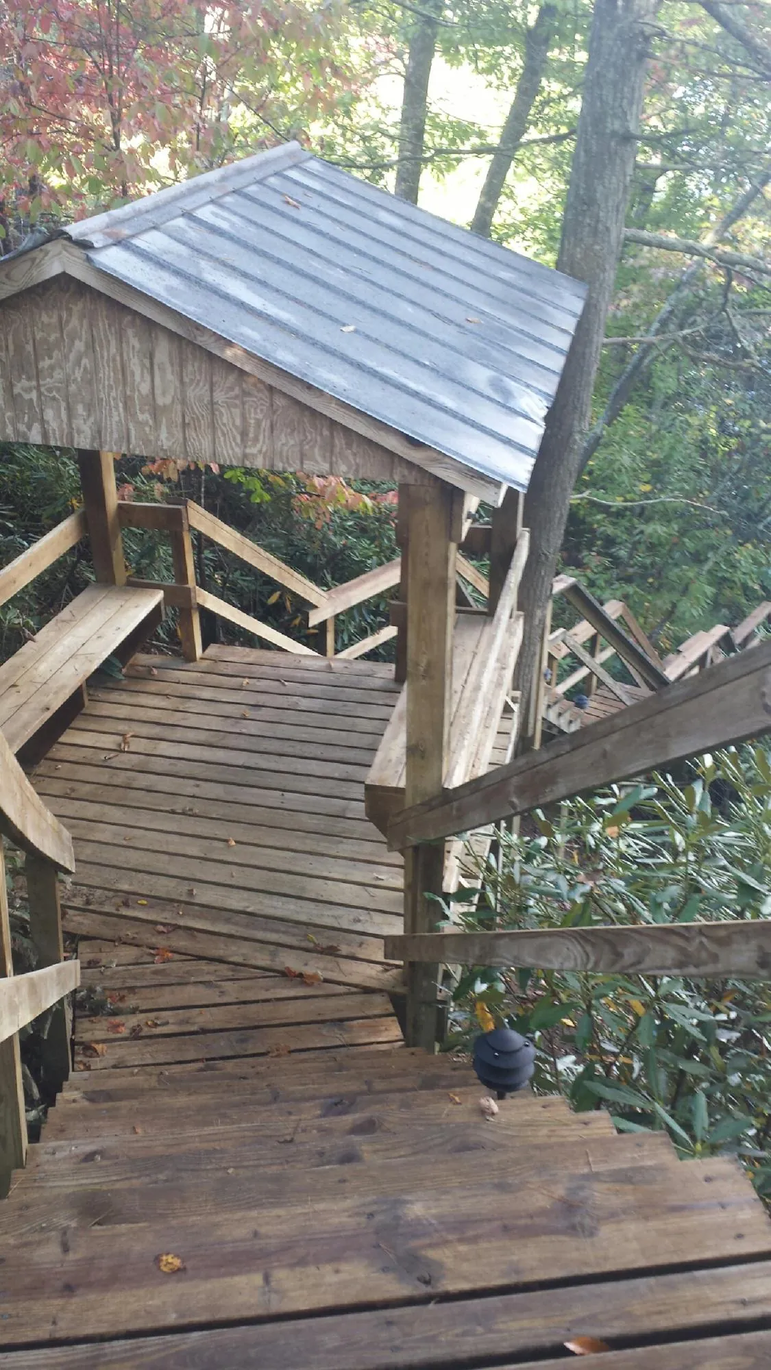 Metal roofed shelter over wooden steps on a wooded walkway — Skylight Repair & Installation work by our crew in Stoneham