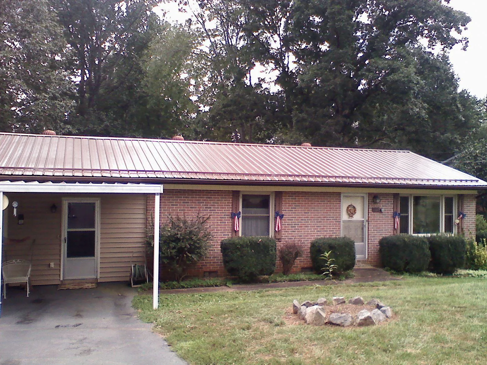 Bronze metal roof and carport on a brick ranch home — Roof Repair work by our crew in Stoneham
